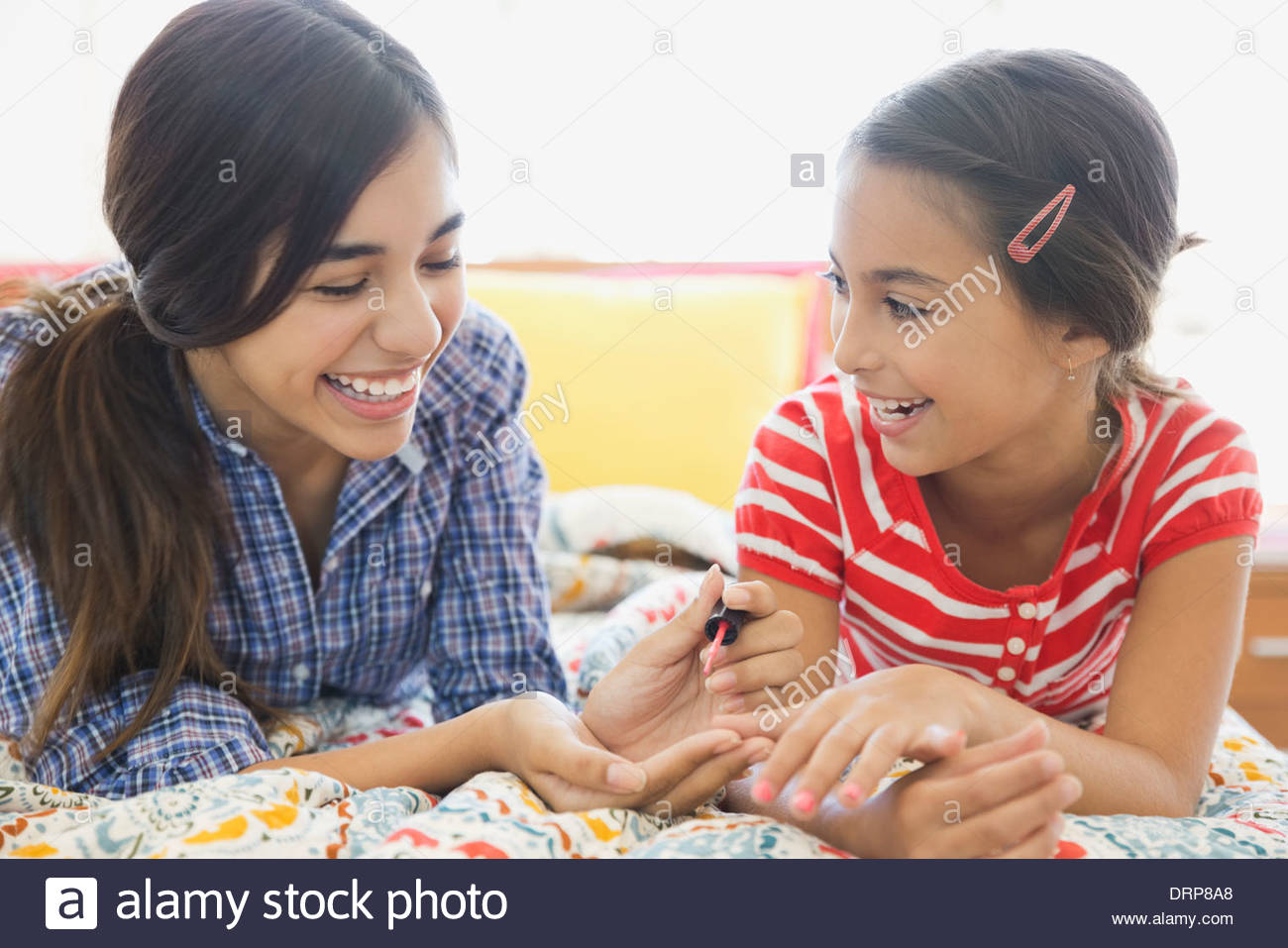 Sisters painting fingernails on bed Stock Photo