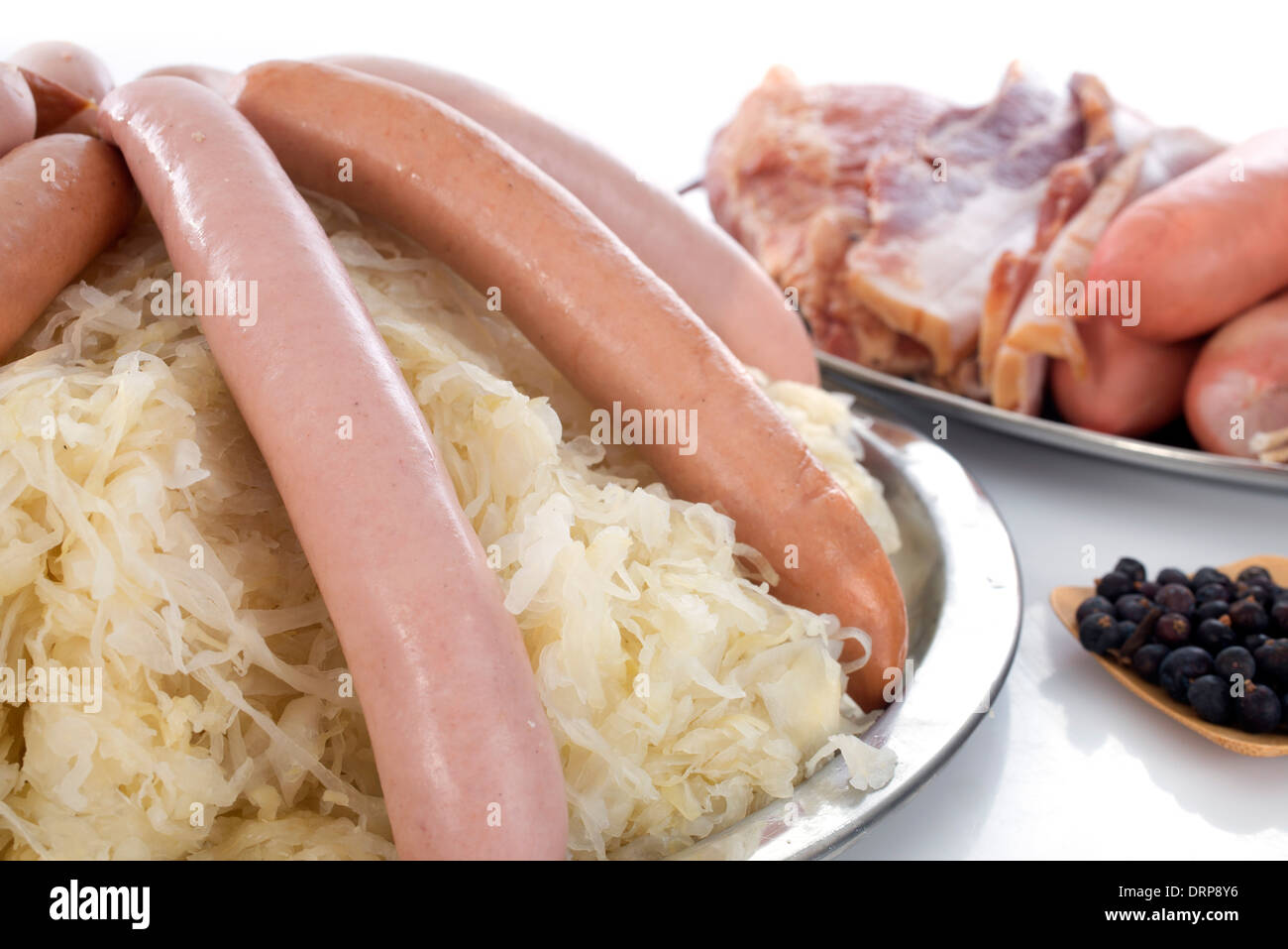 Sauerkraut and cooked meats in front of white background Stock Photo