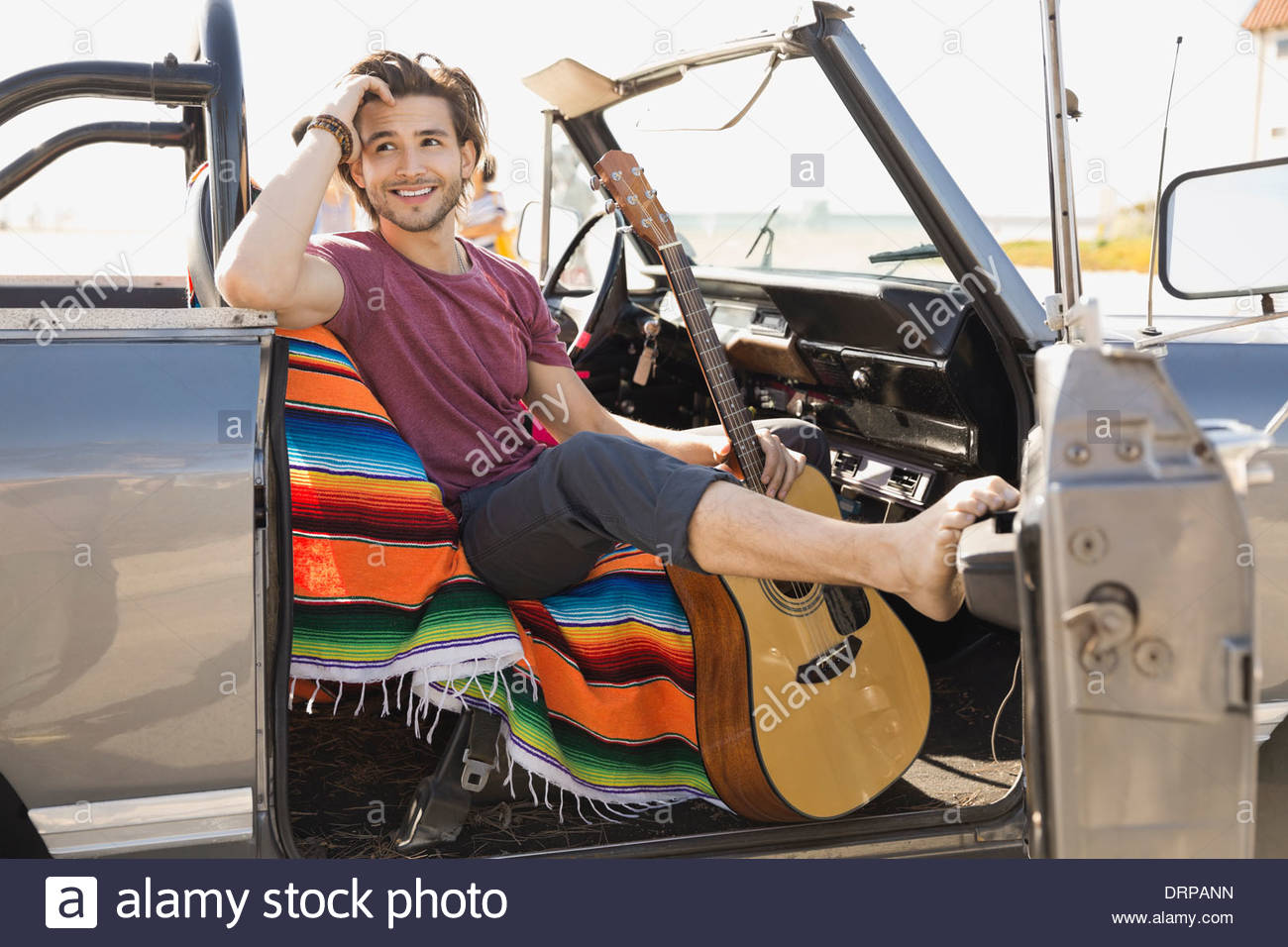 Man with guitar sitting in off-road vehicle Stock Photo