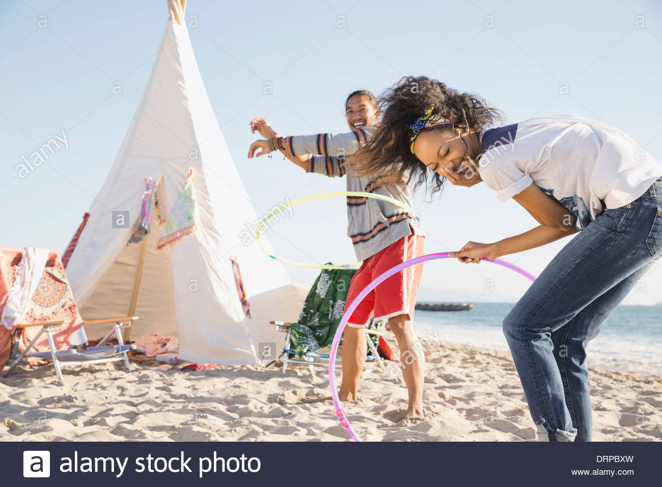 Couple hula hooping on beach Stock Photo