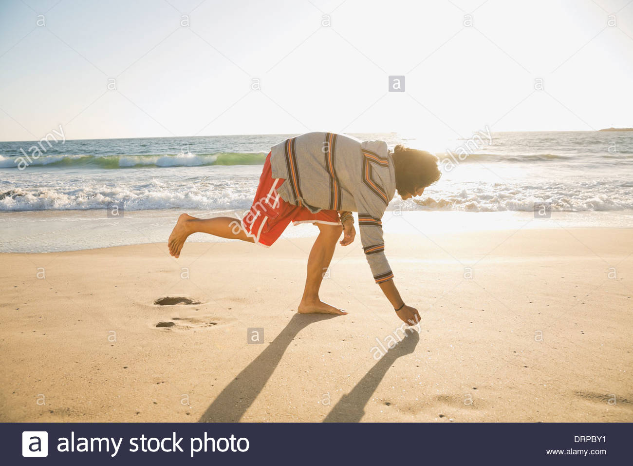 Man picking up shells at beach Stock Photo