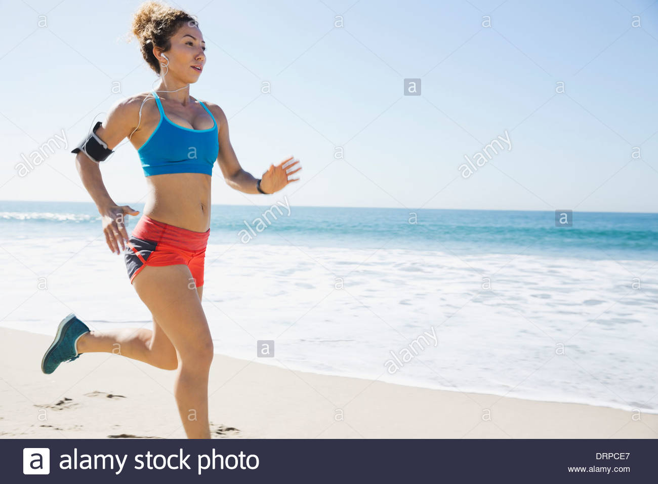 Determined jogger listening to music at beach Stock Photo