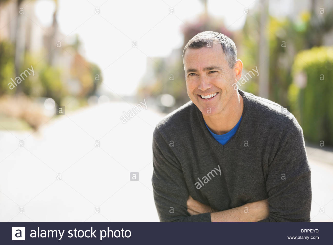 Man with arms crossed standing on street Stock Photo