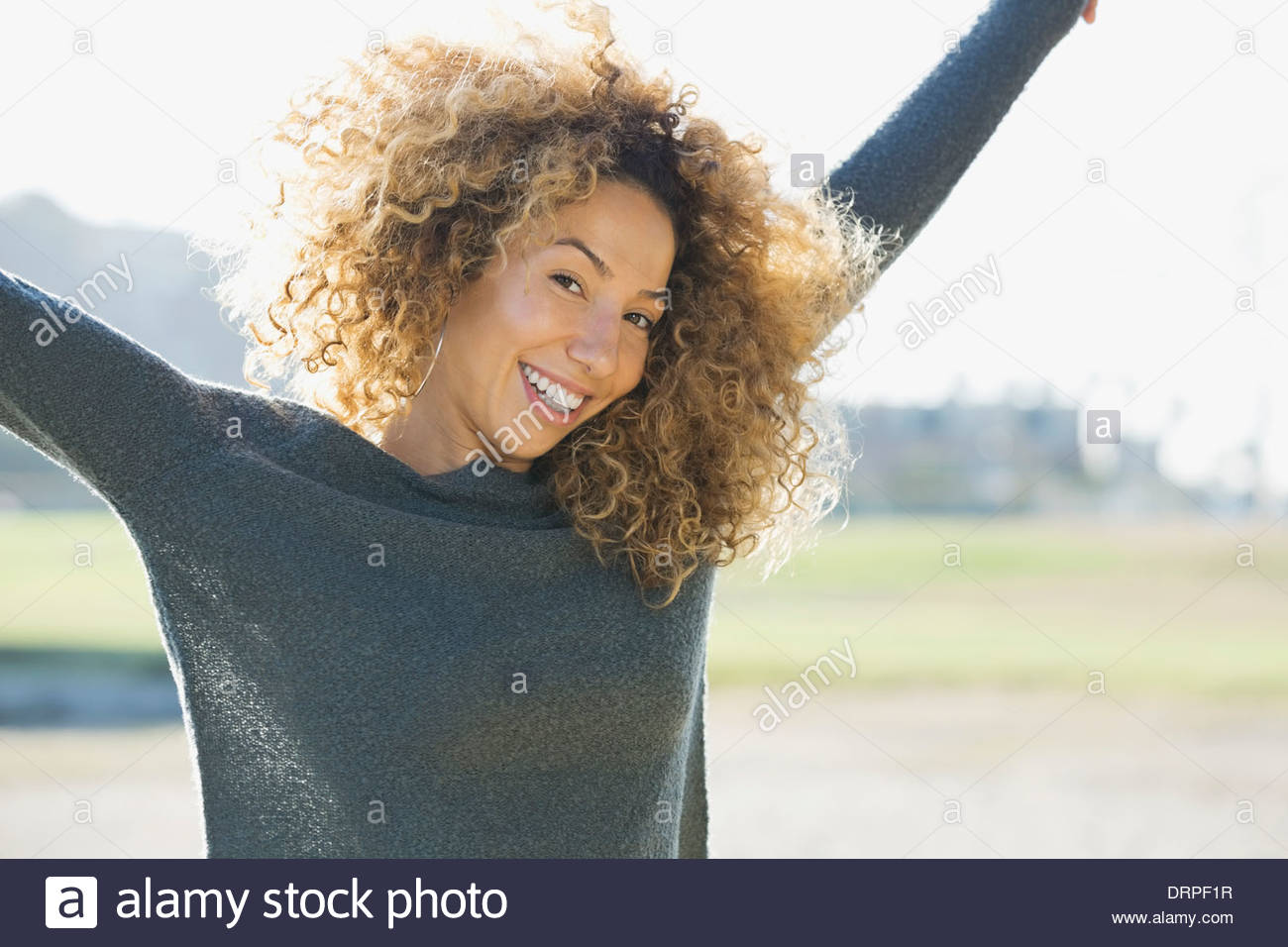 Portrait of woman with arms raised outdoors Stock Photo
