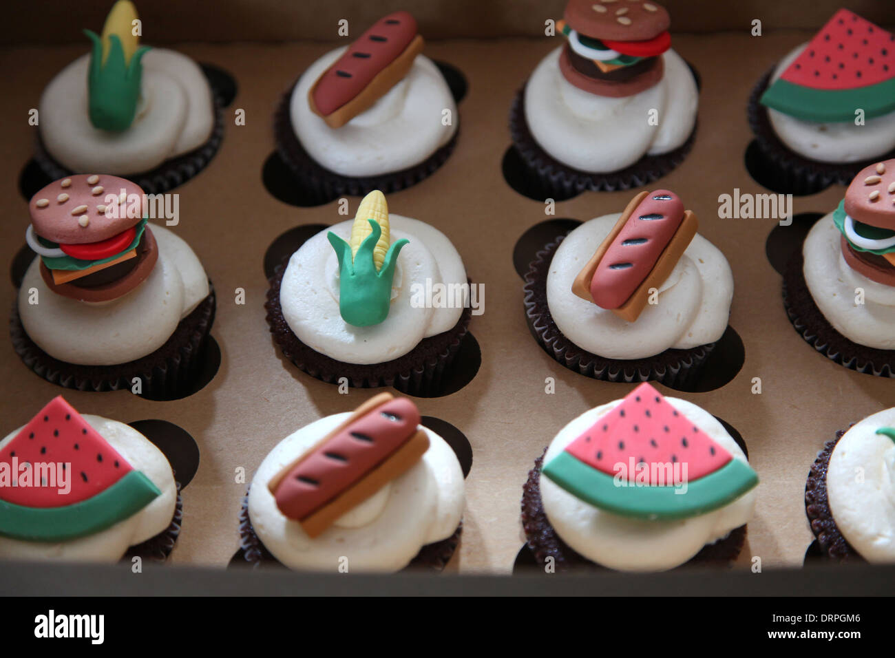 Chocolate cupcakes with vanilla butter cream frosting and gum paste hamburgers, hot dogs, corn and watermelon Stock Photo
