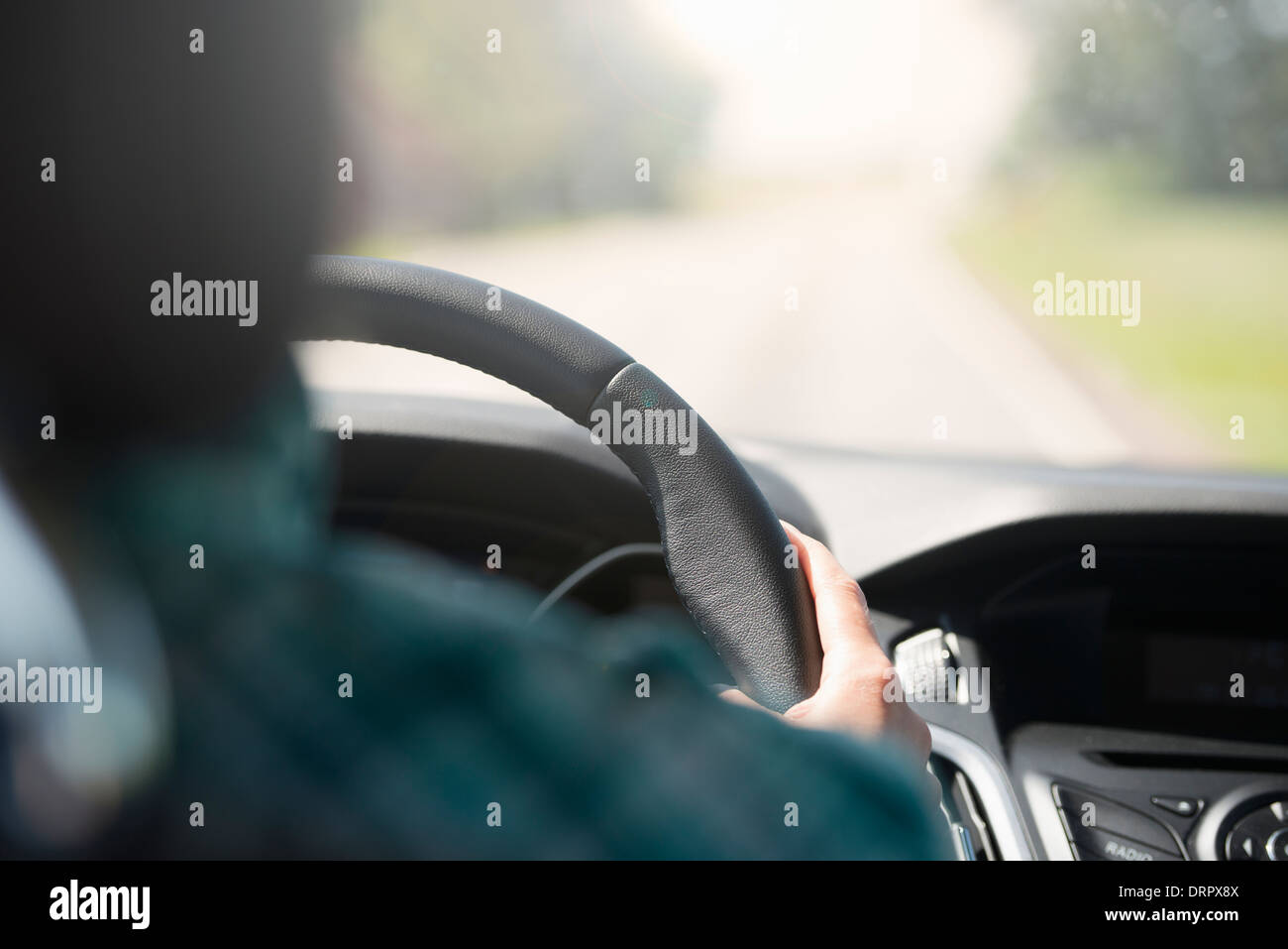 Person on a journey, driving a car. Holding the steering wheel and looking at an empty road. Stock Photo