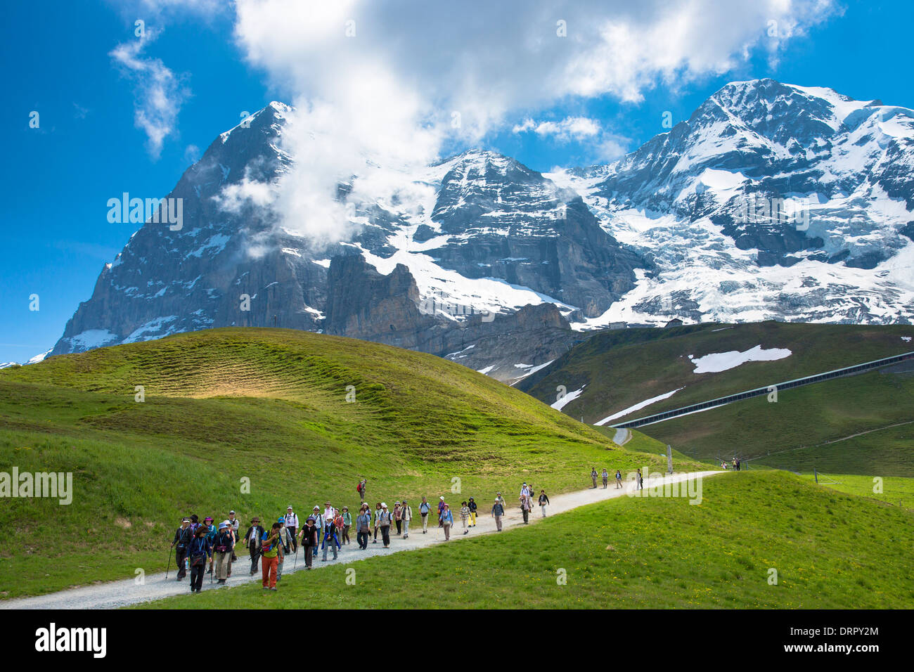 Japanese tourists on walking trail by the North Face of the Eiger mountain in the Swiss Alps, Bernese Oberland, Switzerland Stock Photo