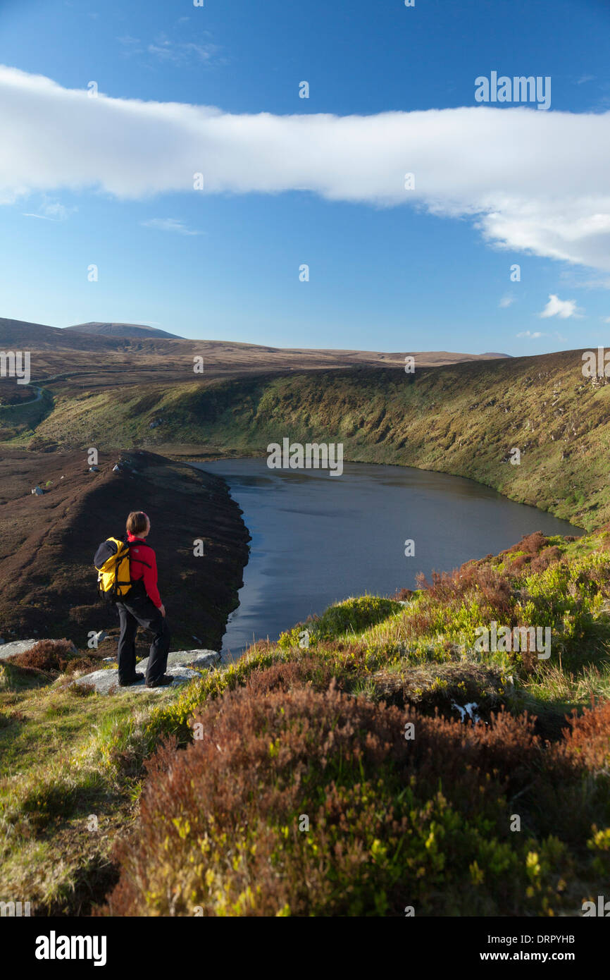 Walker looking over Lough Bray Upper, Kippure, Wicklow Mountains National Park, County Wicklow, Ireland. Stock Photo