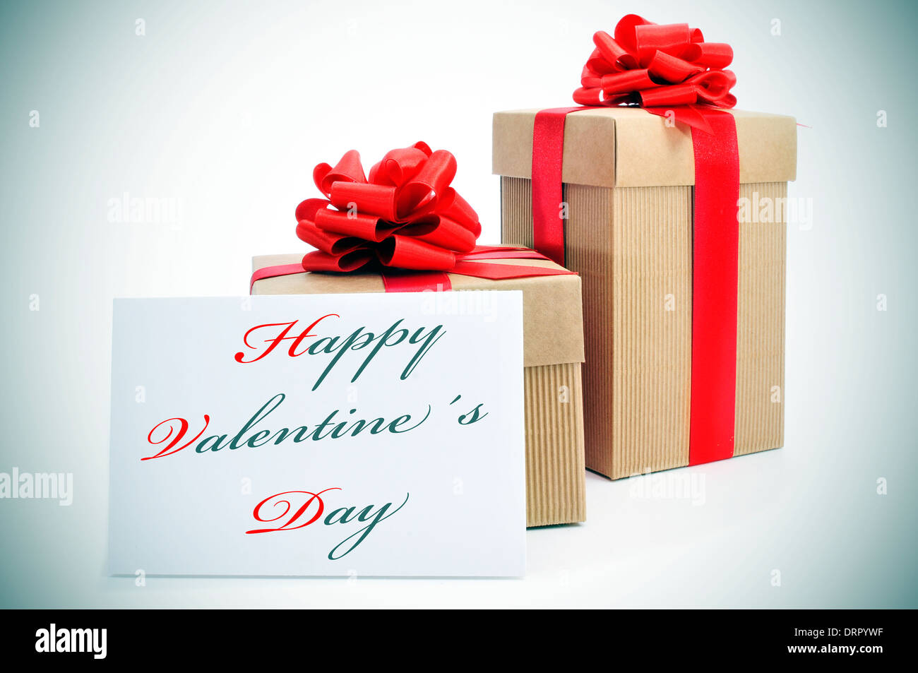 some gifts with red ribbon and a the sentence happy valentines day written in a signboard Stock Photo