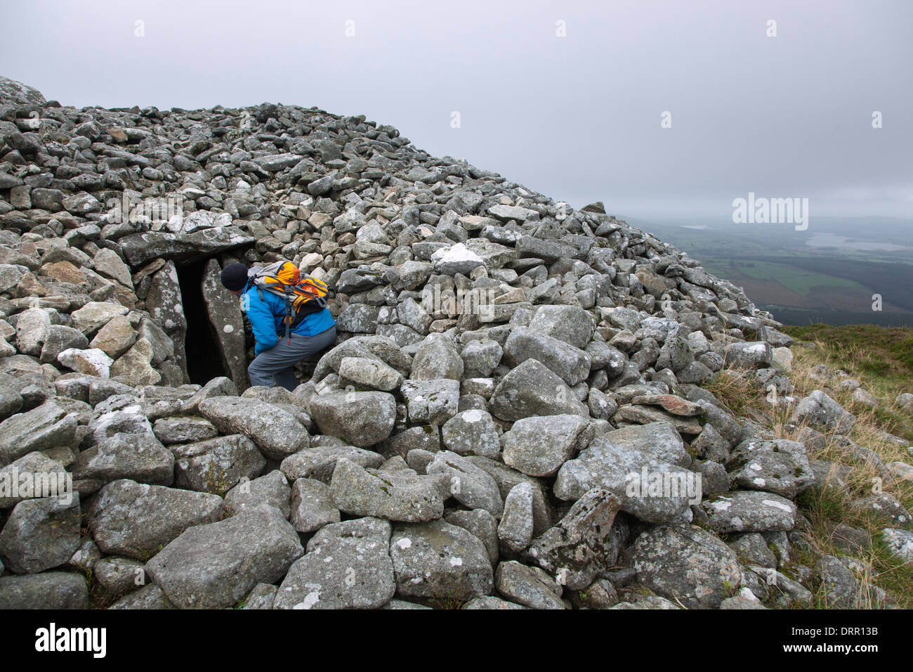 Walker examines the entrance to a neolithic tomb at the summit of Seefin (621m), Wicklow Mountains, County Wicklow, Ireland. Stock Photo