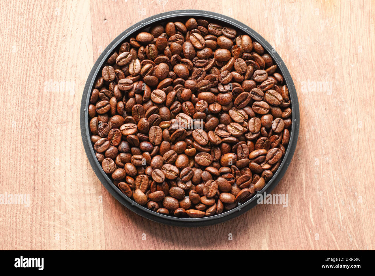 An abundance of roasted coffee beans in a circular bowl. Stock Photo