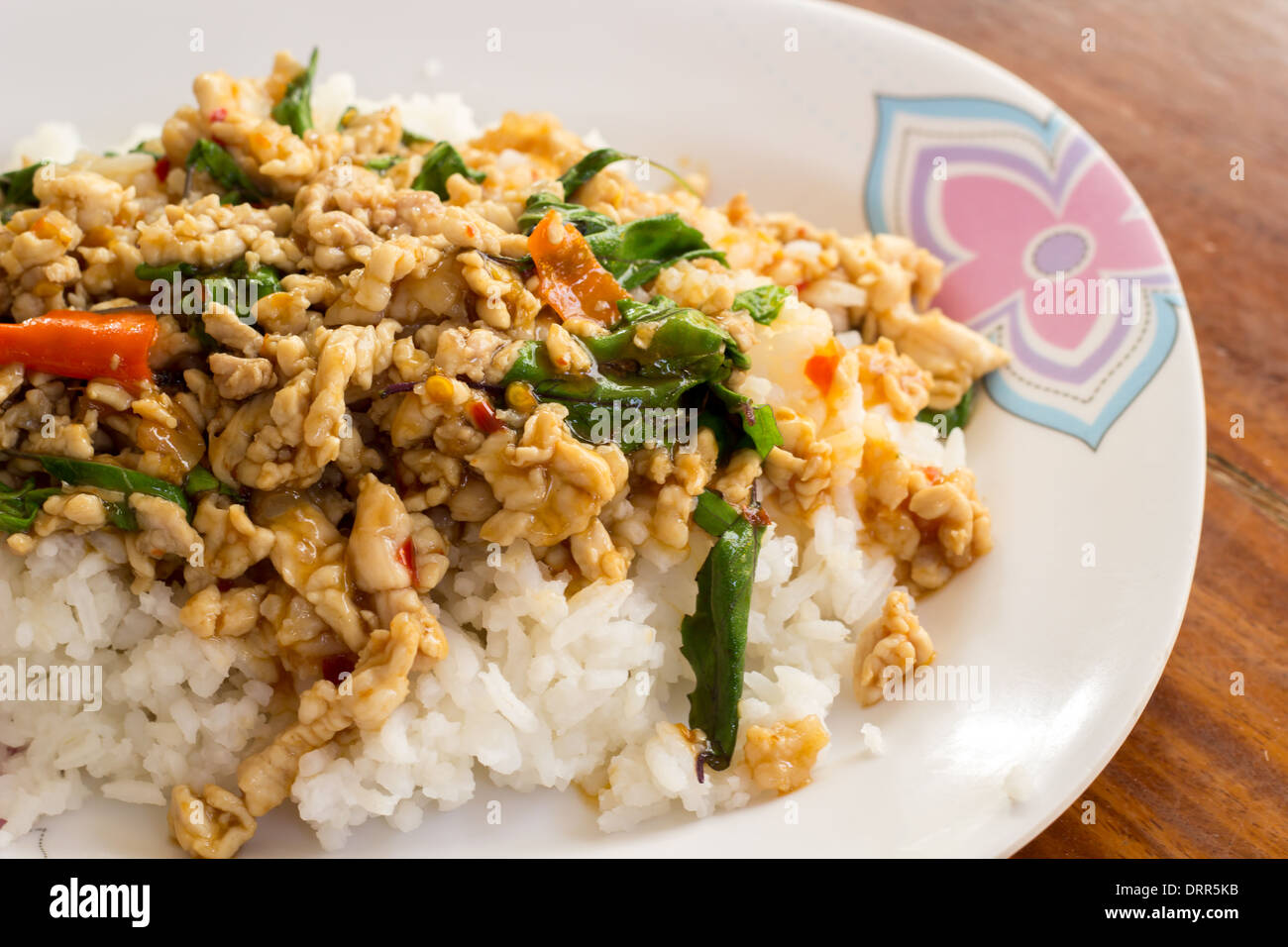 The Fried rice with basil on a white plate on a wooden table. Stock Photo
