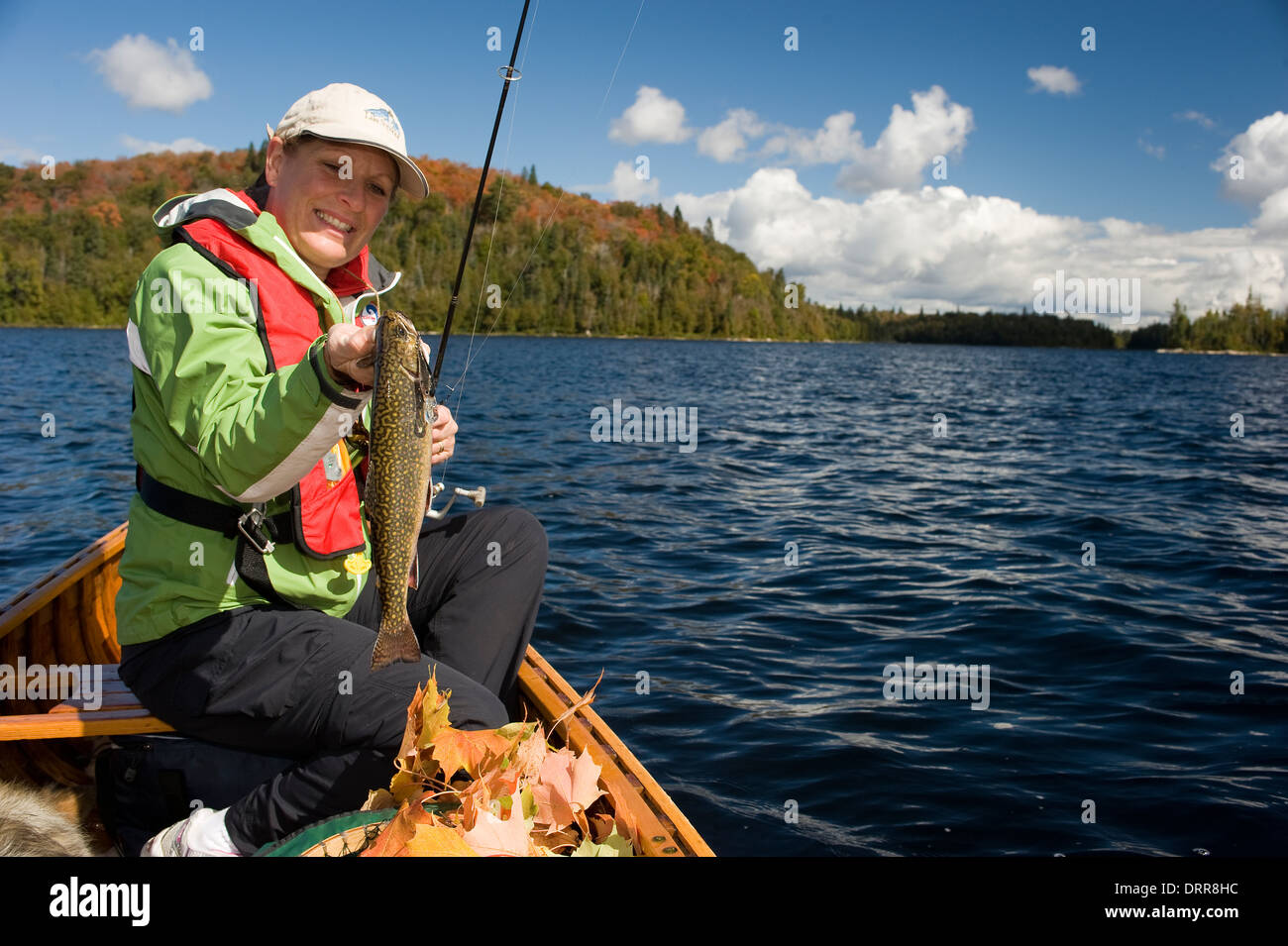Woman angler holding summer brook trout caught while canoeing in