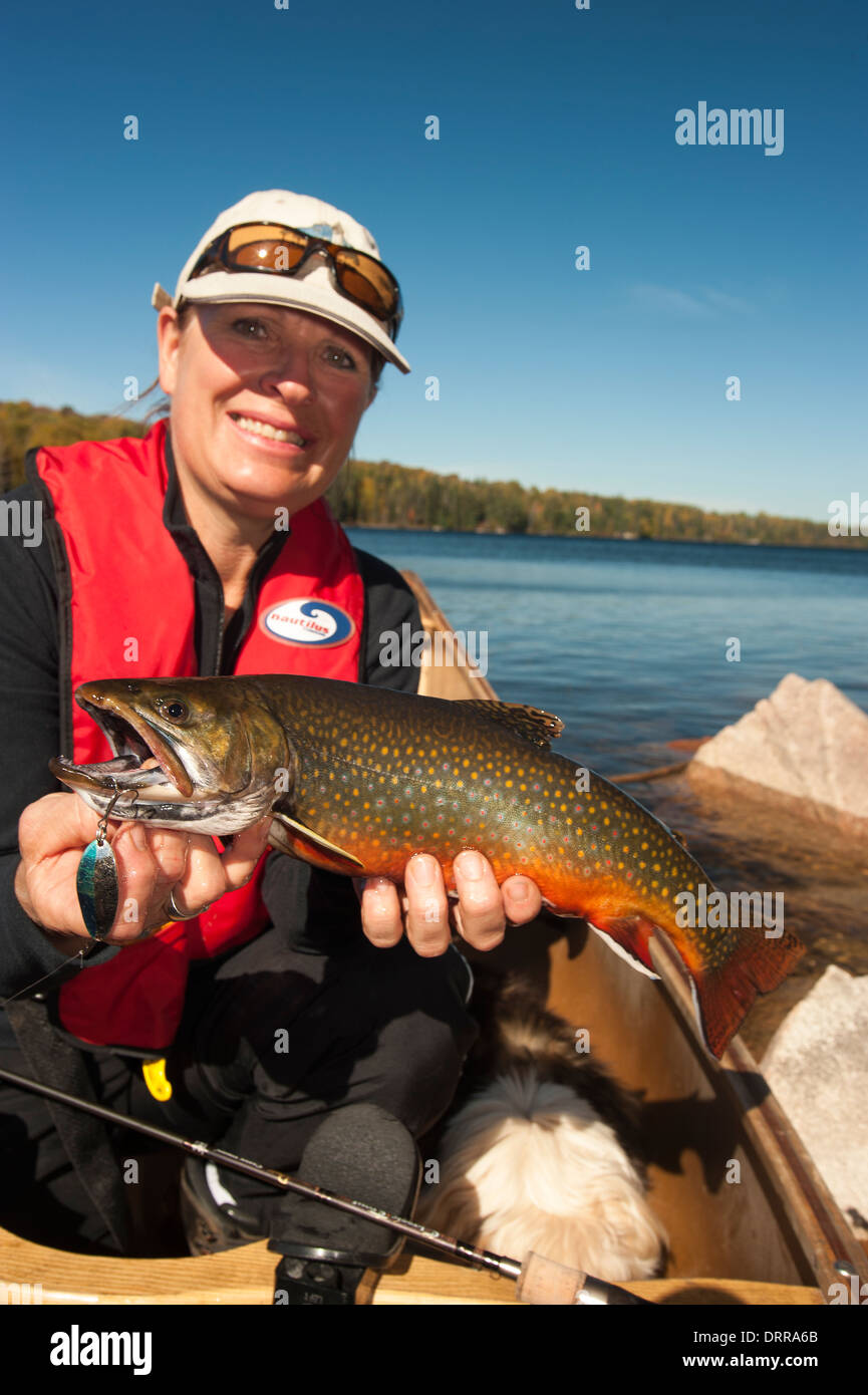 Woman angler holding a summer brook trout she caught in a lake in
