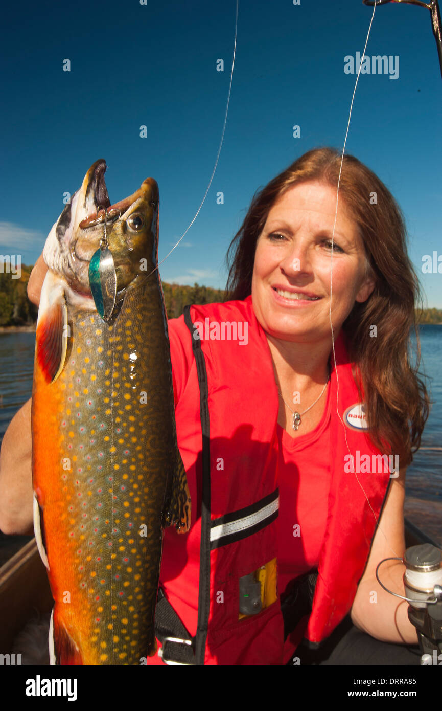 Woman angler holding a summer brook trout she caught in a lake in