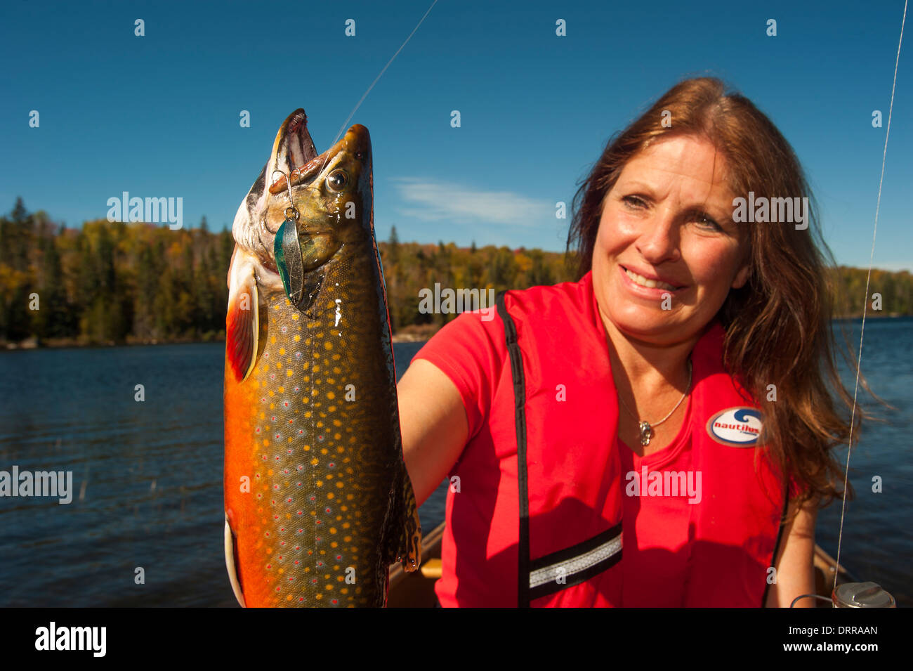 Woman angler holding a summer brook trout she caught in a lake in