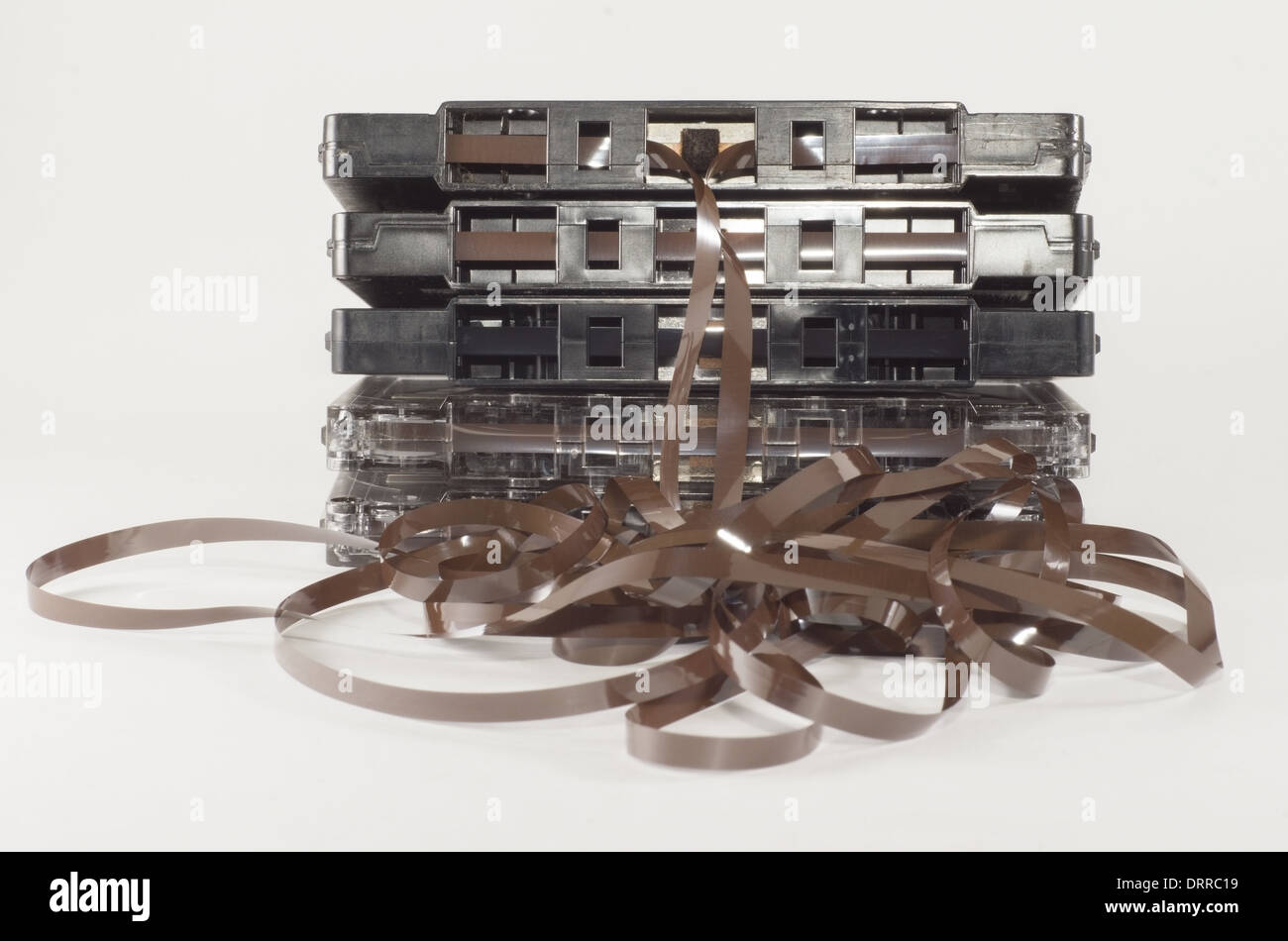 A stack of audio tapes with unwound tape hanging from top tape Stock