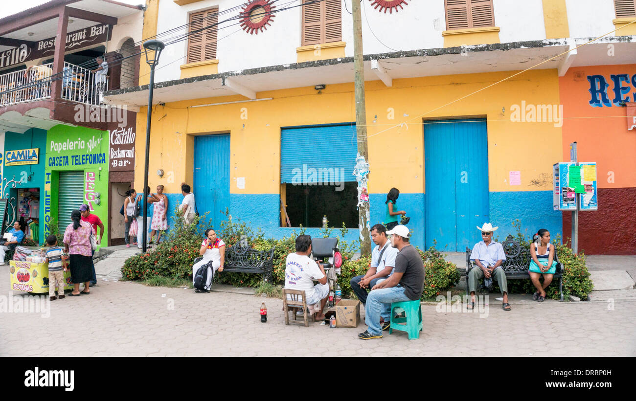 people & vendors gather in public plaza in front of colorfully painted buildings in regional commercial center generally unattractive town of Pochutla Stock Photo