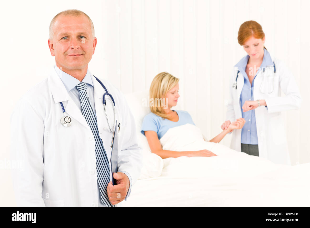 Two doctors with patient lying in bed Stock Photo Alamy