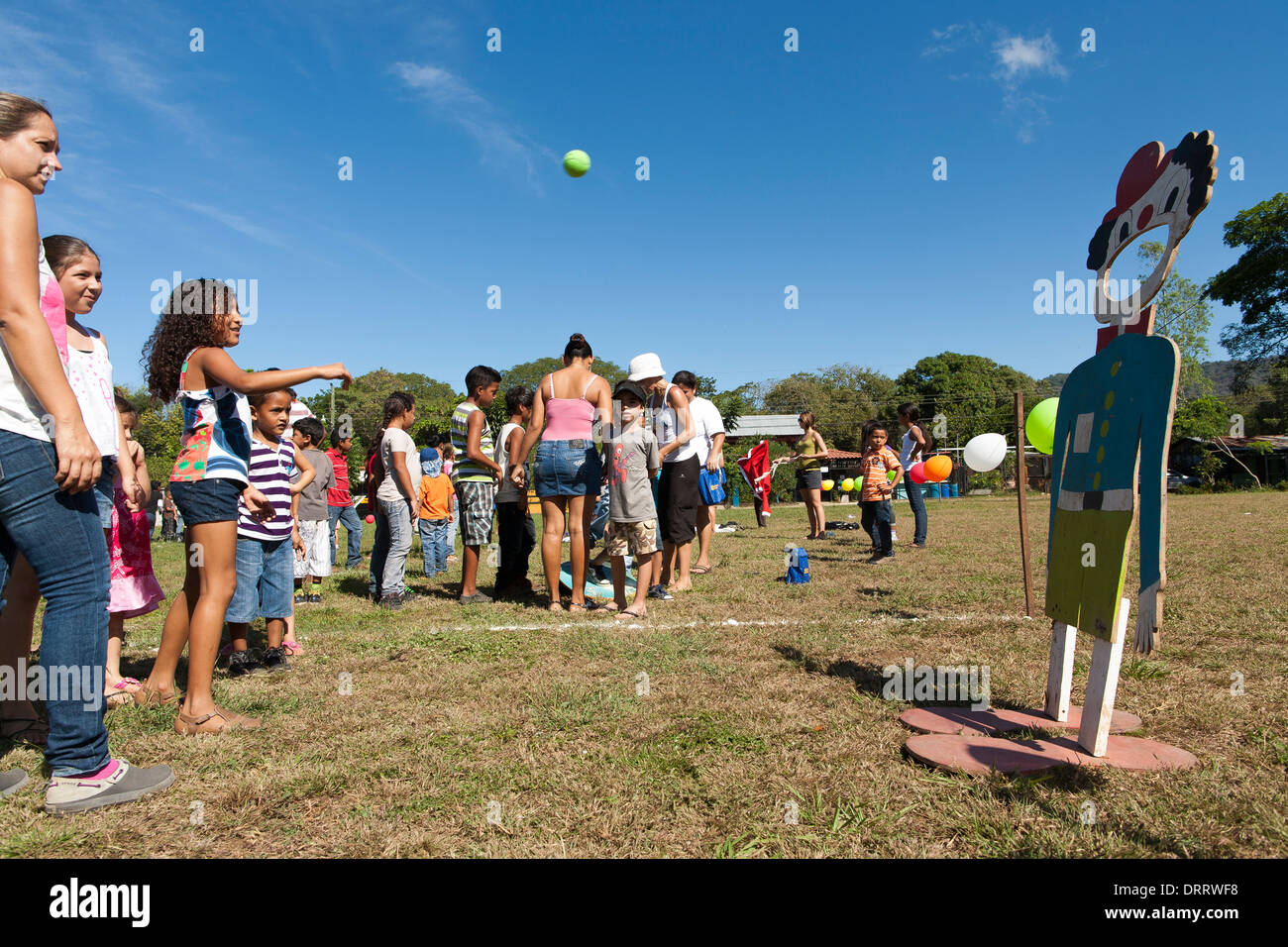 Children play throwing a ball clown with big mouth at community games