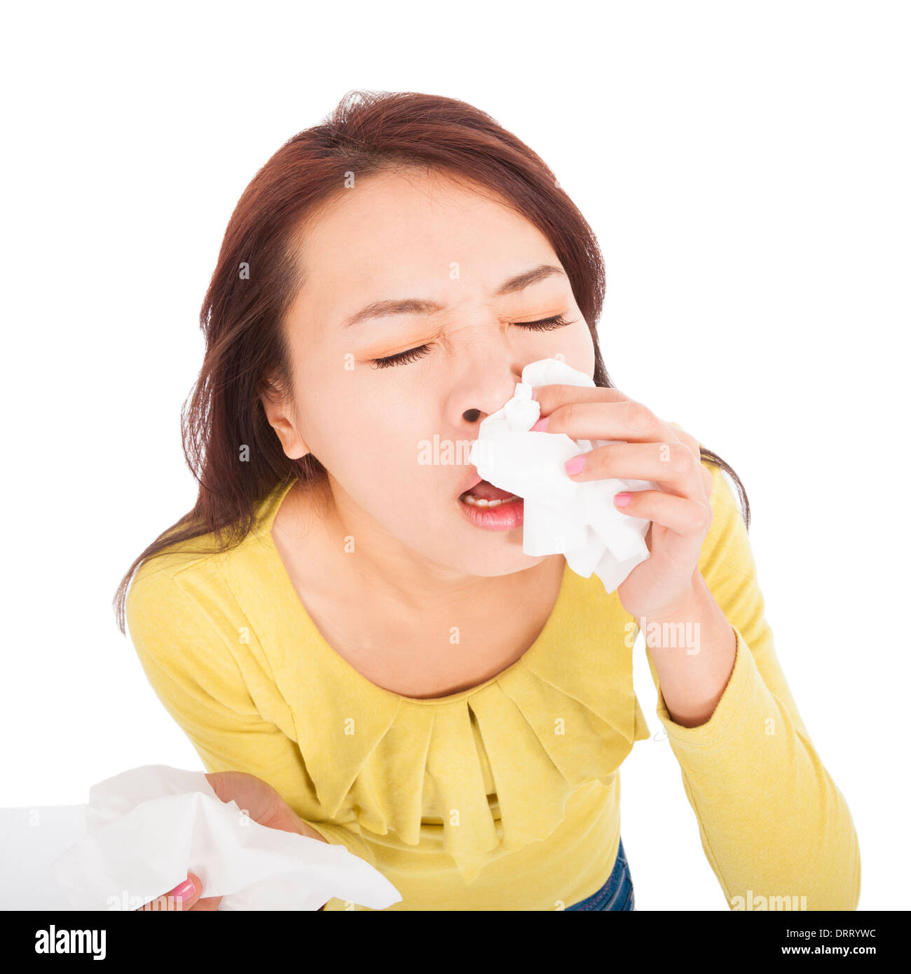 young woman with a an allergy sneezing into tissues Stock Photo