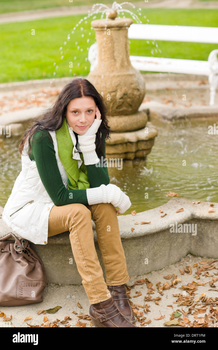 Autumn park young woman sit on fountain Stock Photo - Alamy