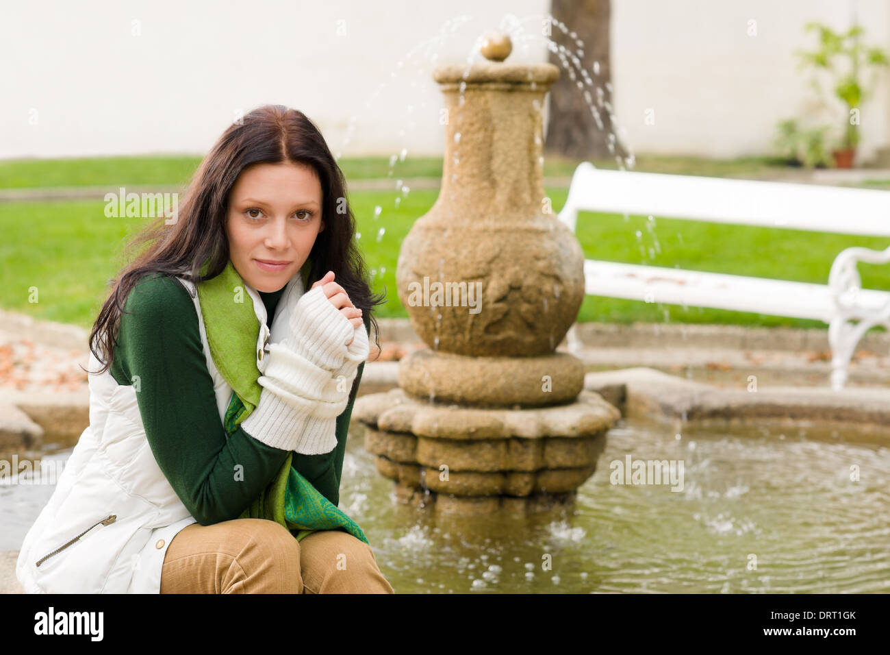Autumn park young woman sit on fountain Stock Photo - Alamy
