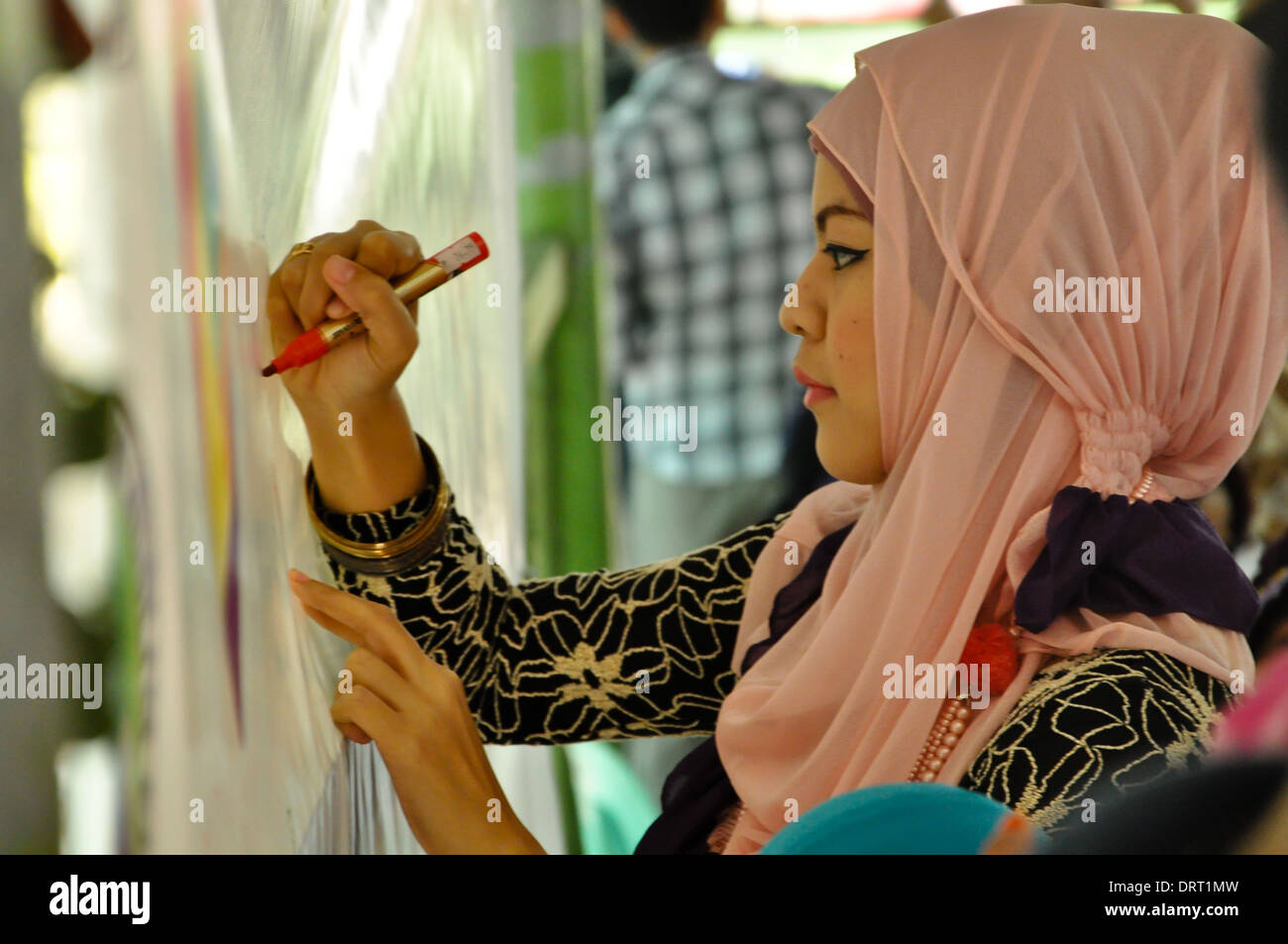 A Hijabi, woman wearing a Hijab, write her pledge during the celebration of World Hijab Day in Quezon City. Stock Photo