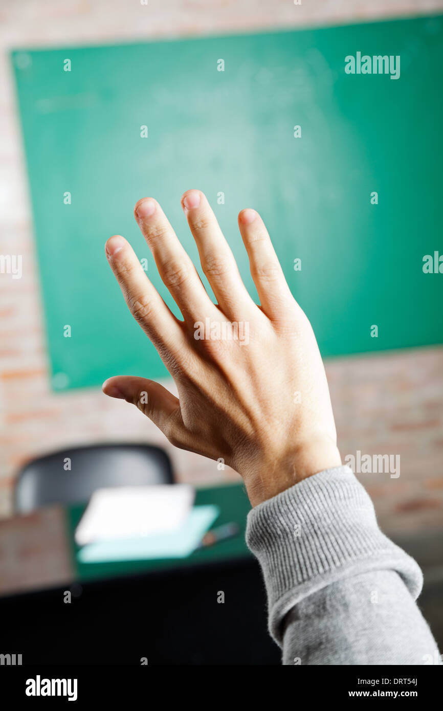 Student's Hand Against Greenboard In Classroom Stock Photo