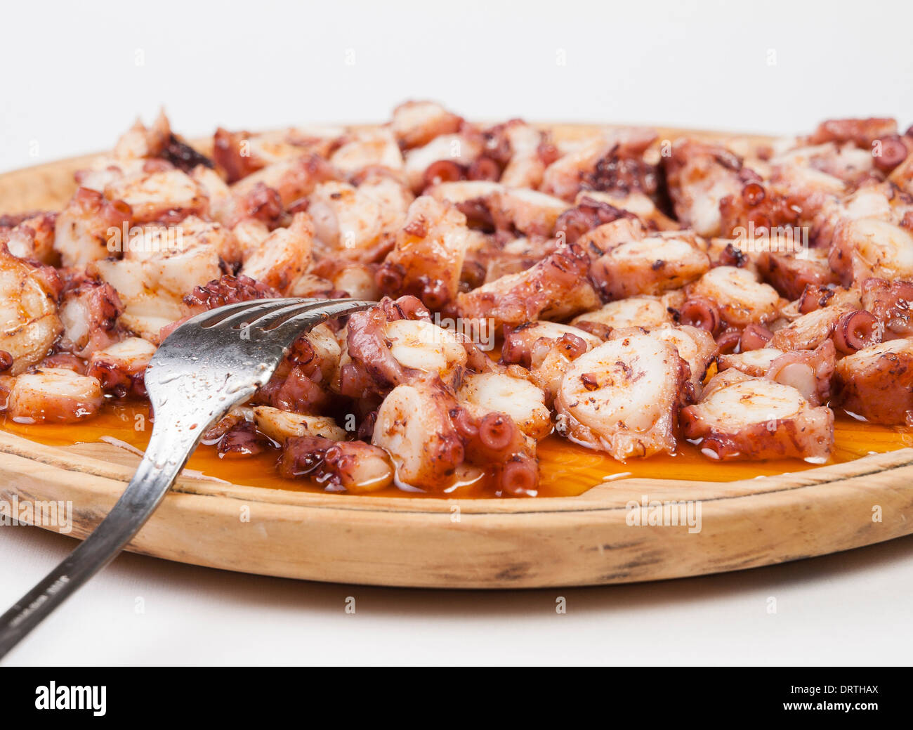 Pulpo a feira in a wooden plate with fork and isolated on white background Stock Photo