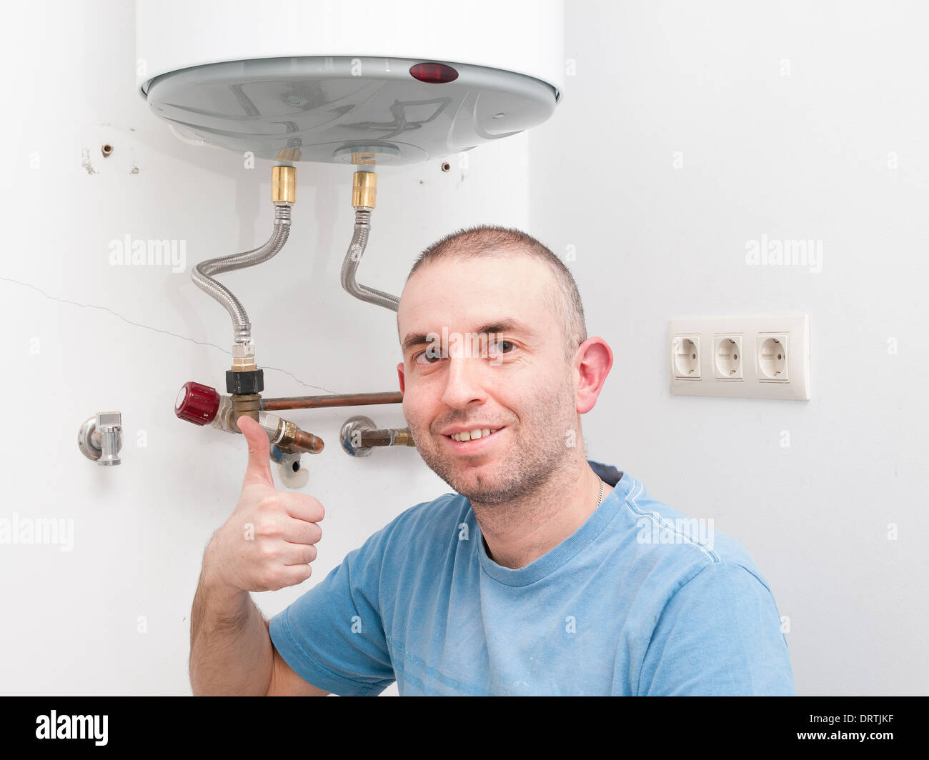 Plumber Man expressing positivity with ok symbol with hand. Man has repaired an electric boiler. Stock Photo