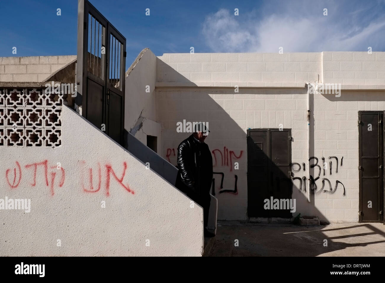 A Palestinian man stands at a house which was spray painted with inflammatory phrases such as 'Death to the Arabs', 'Revenge!' in apparent price tag attack near the Jewish settlement Ma'ale Levona at the West Bank Israel on 31 January 2014. “Price tag” is used to refer to acts of political violence carried out by right-wing Israelis protesting Israeli government policy regarding the settlements and the Palestinians. Stock Photo