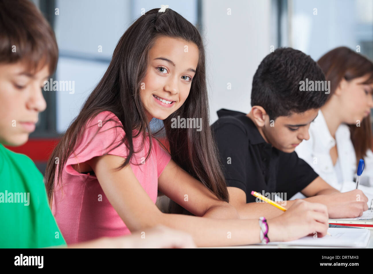 Teenage Girl Sitting With Classmates Studying At Desk Stock Photo - Alamy