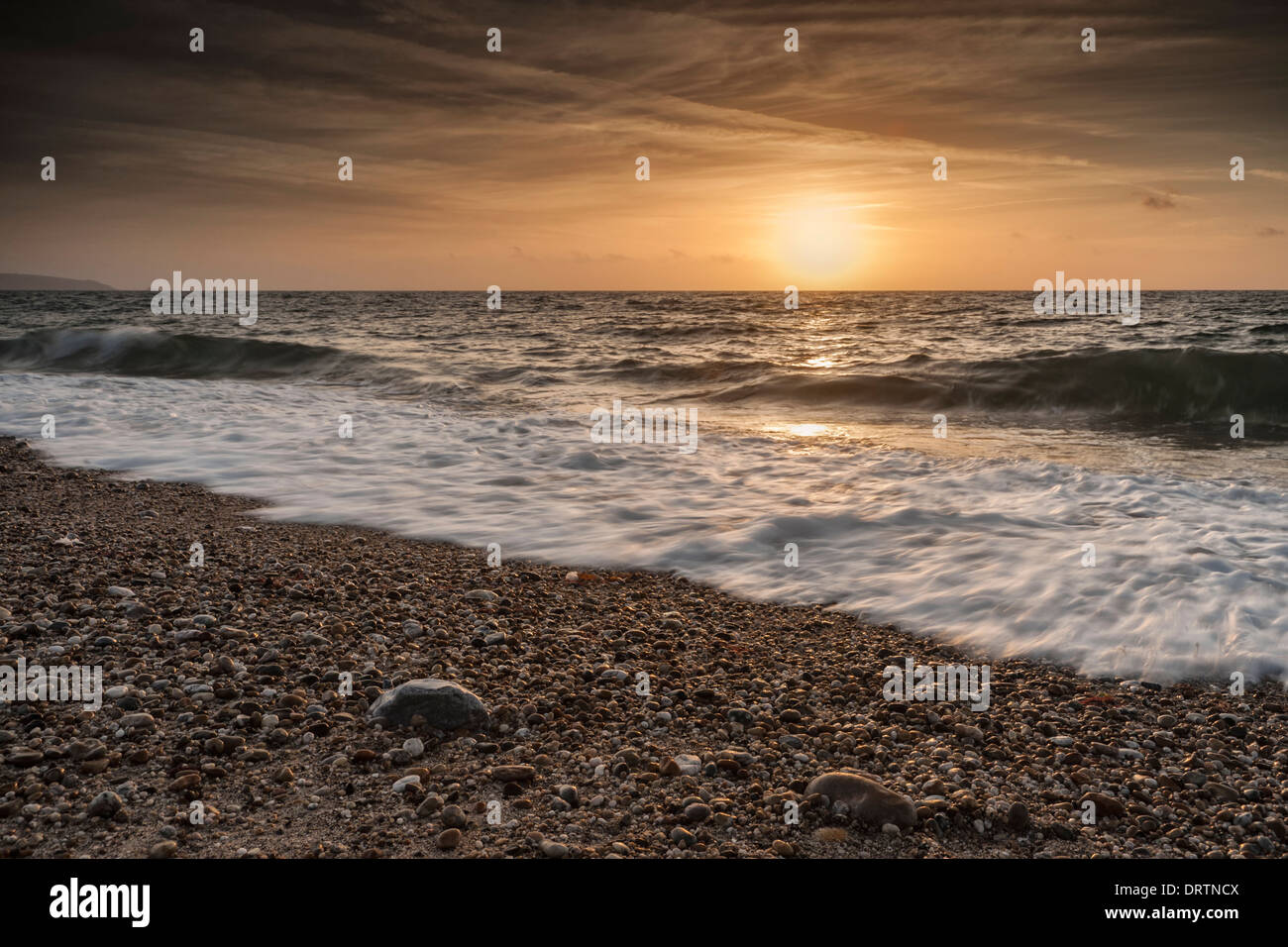 waves washing up the beach over the sand and pebbles at Beesands in Kingsbridge at sunrise on a summers day. Stock Photo