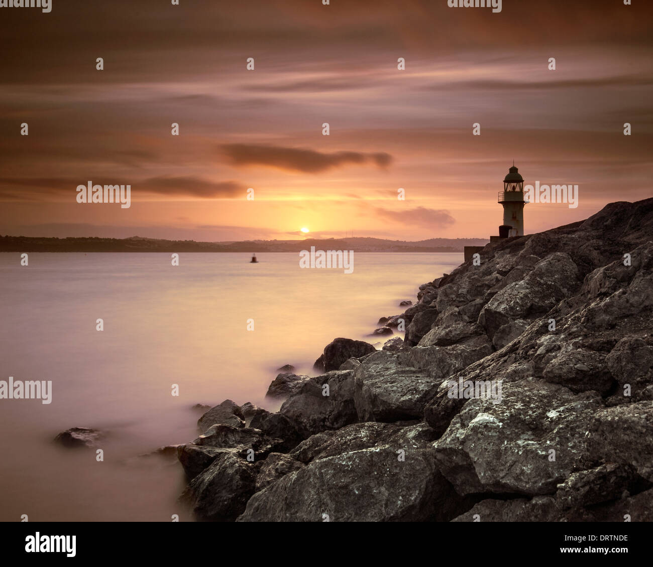 Brixham lighthouse at the end of the breakwater at sunset. Stock Photo