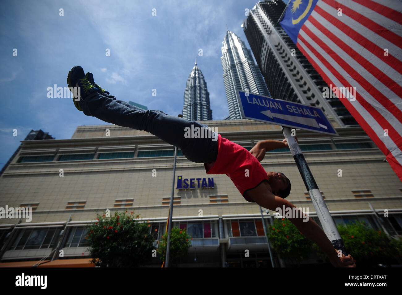 Kuala Lumpur, Malaysia. 1st Feb, 2014. A man does a flag stand in front of Kuala Lumpur Twin Towers on the second day of Chinese Lunar New Year in Kuala Lumpur, Malaysia, Saturday, February 1, 2014. In Malaysia, during religious festivities there is usually two days public holiday, which other ethnic races will enjoy the holidays. © Joshua Paul/NurPhoto/ZUMAPRESS.com/Alamy Live News Stock Photo