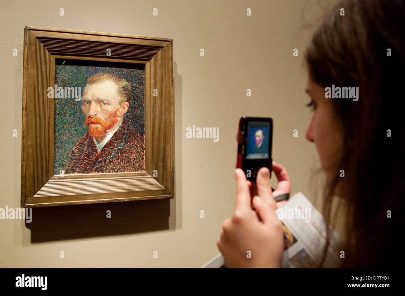 A pretty brunette girl takes a picture of "Self-Portrait", by Vincent van Gogh, in The Art Institute of Chicago art museum. Stock Photo