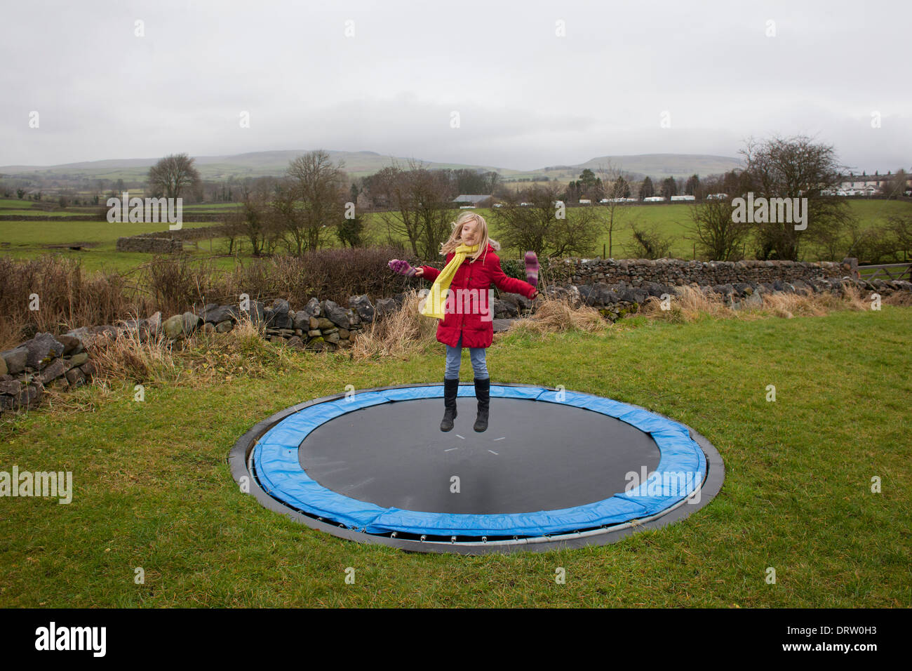 A young blonde girl bounces on a trampoline in the English countryside  Stock Photo - Alamy