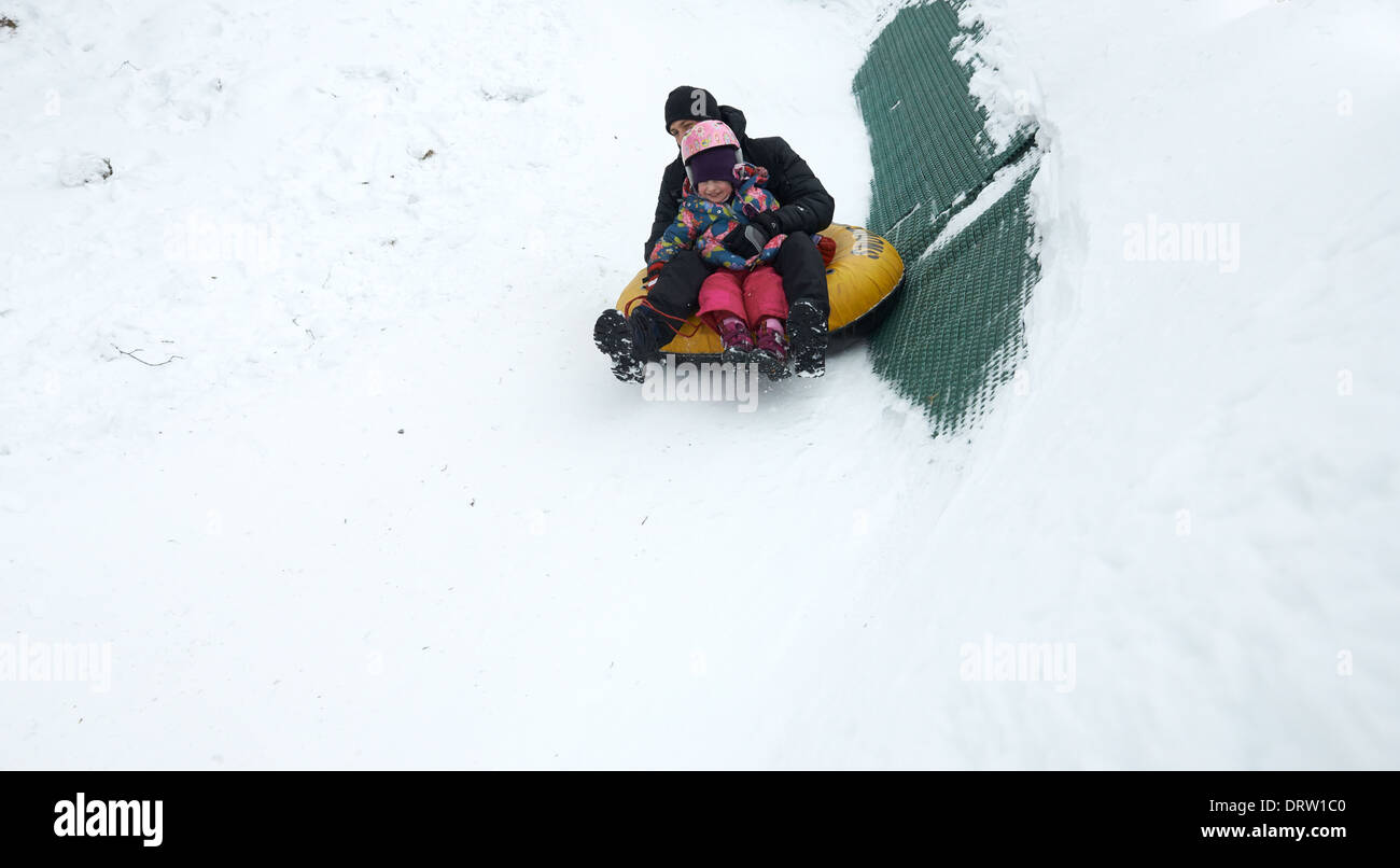 Father and daughter having fun in snow inner tube snowtubing Stock