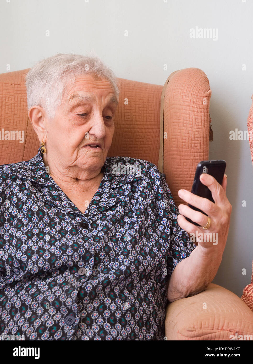 Elderly woman looking at a smartphone inside her home. Stock Photo