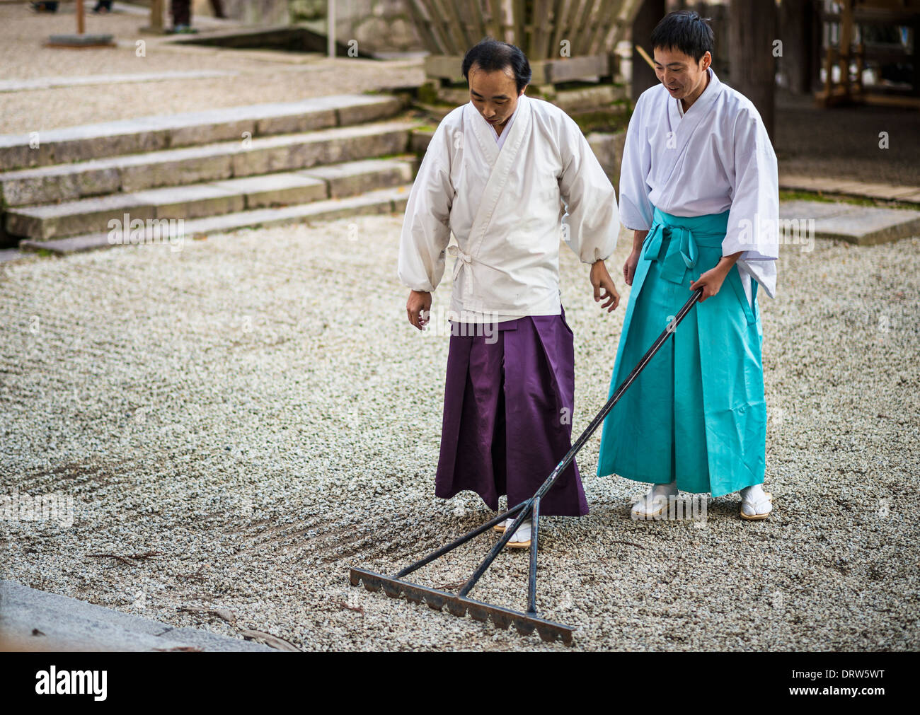Japanese Shinto priests rake a rock zen garden. Stock Photo