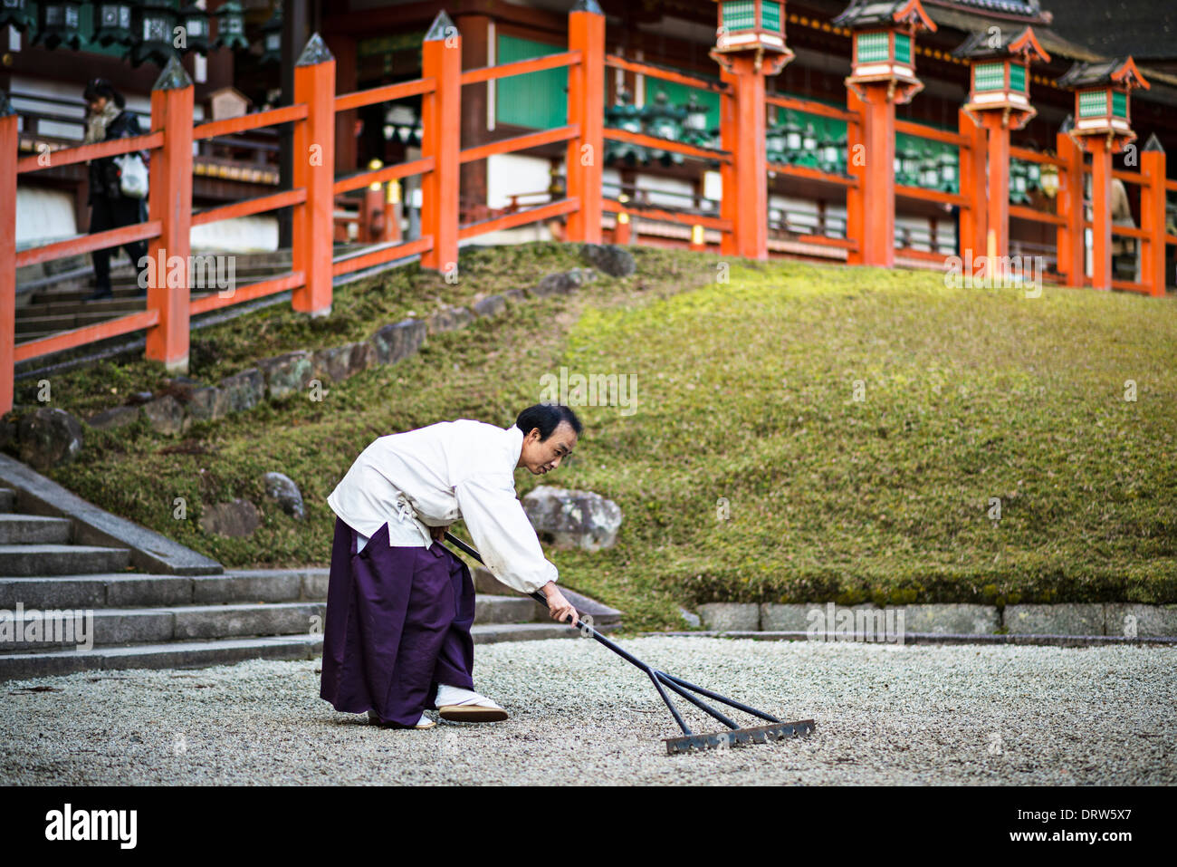 Japanese Shinto priest rakes rock zen garden. Stock Photo