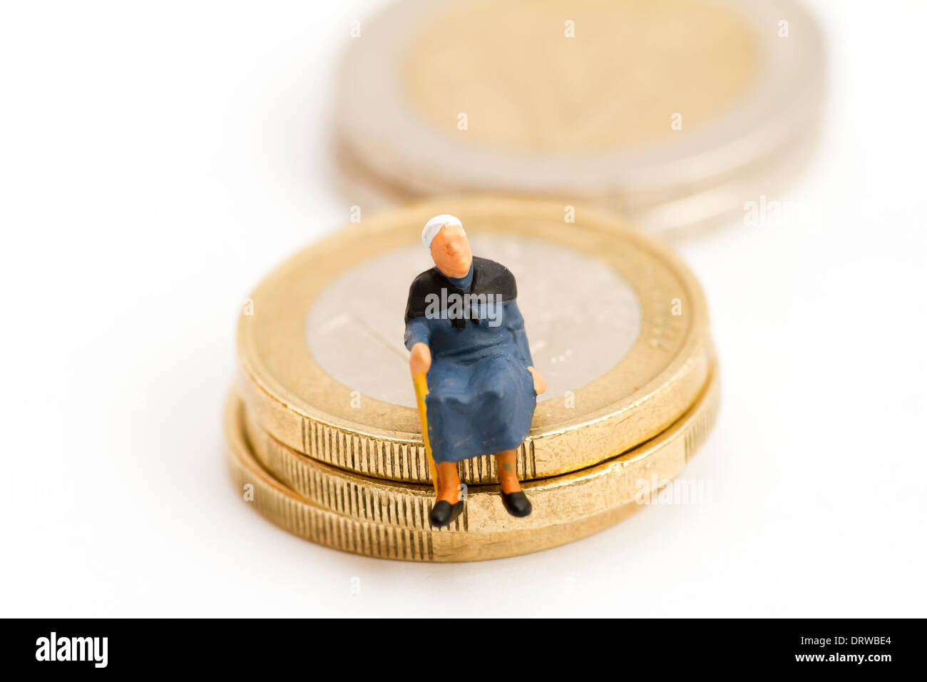 Seniors sitting on stack of coins Stock Photo