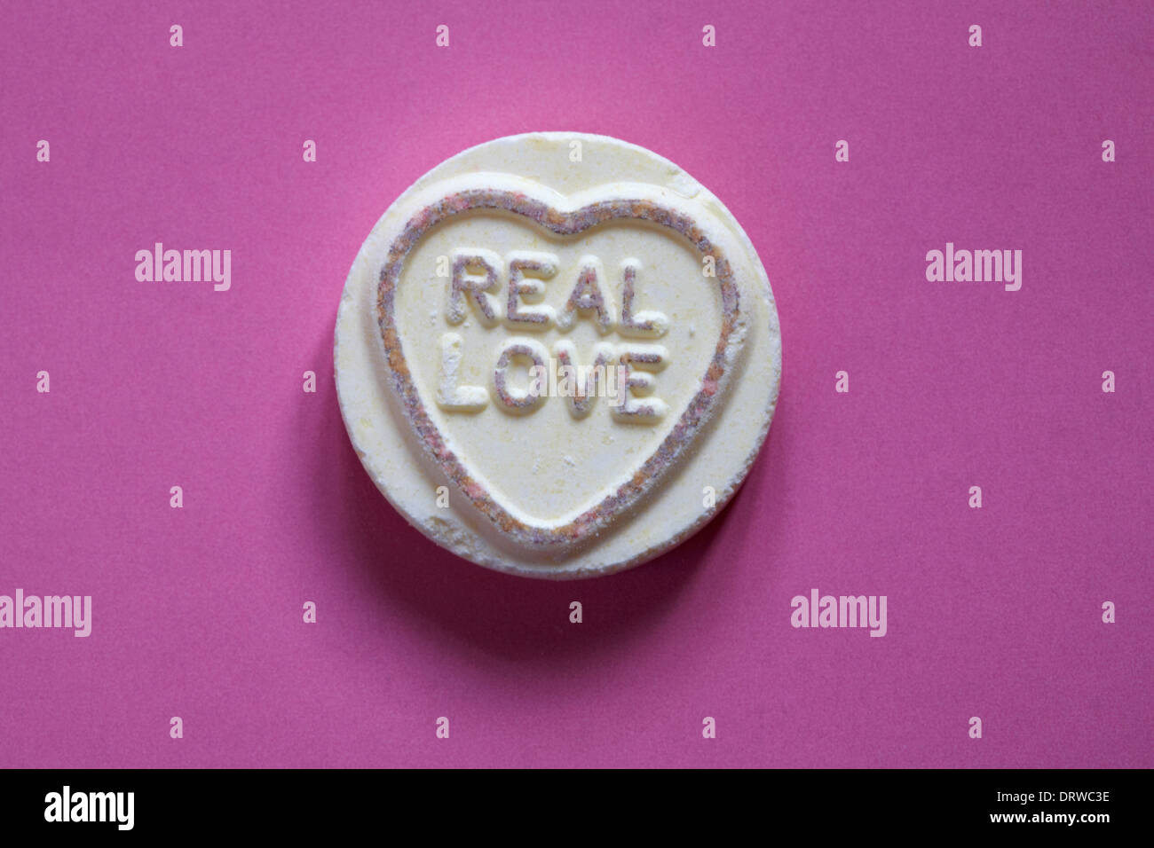 Swizzels Matlow Giant Love Hearts - individual sweet with Real love isolated on pink background - Valentine Day message - loveheart sweets Stock Photo