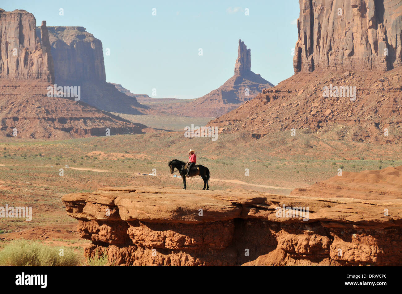 Monument Valley with Red Indian cowboy on black stallion on rock where John Ford shot John Wayne in the movie Stagecoach Stock Photo