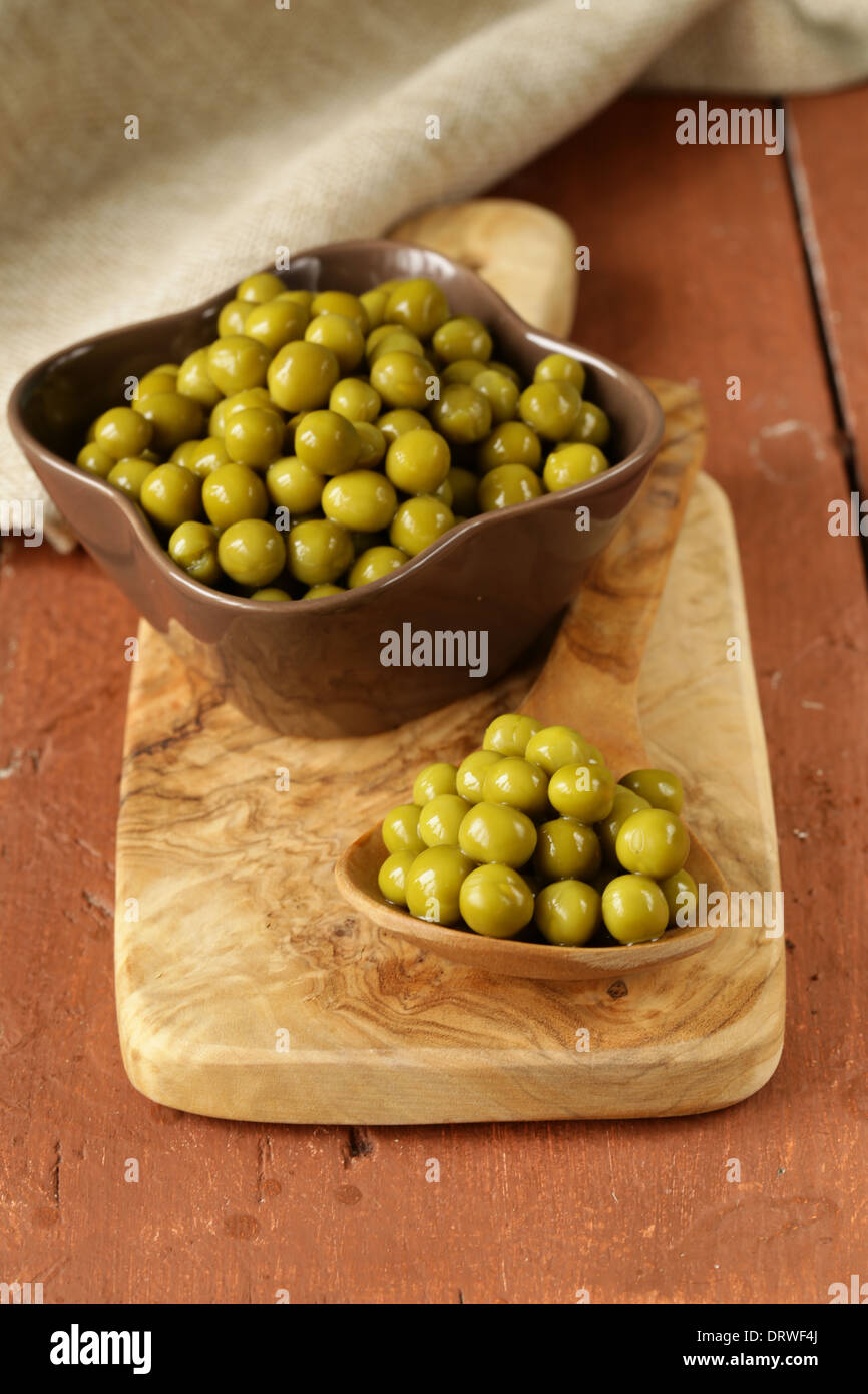 canned green peas in a wooden spoon Stock Photo