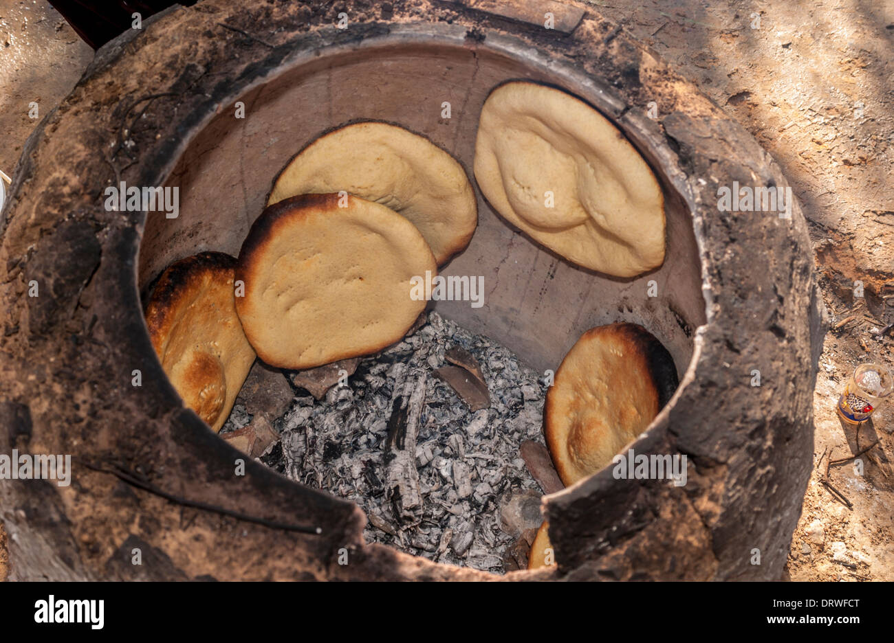 Flatbreads cooking on inside walls of an outdoor Tandoor oven, Tunisia. Stock Photo