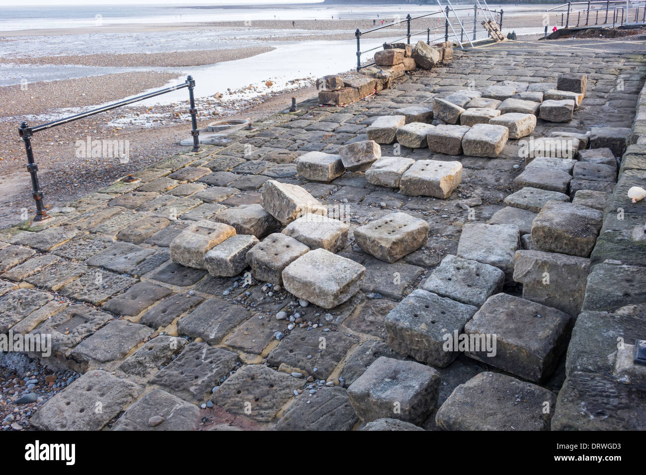Stone blocks formerly used to support railway lines used in a beach walkway in Saltburn being rebuilt after storm damage Stock Photo
