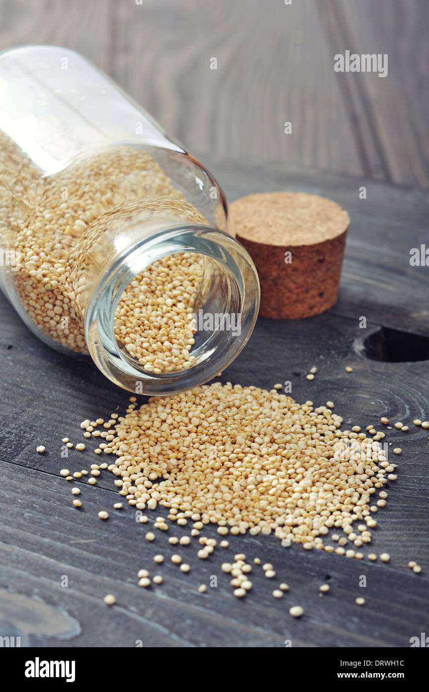 Raw quinoa seeds in the glass bottle on wooden background closeup Stock Photo