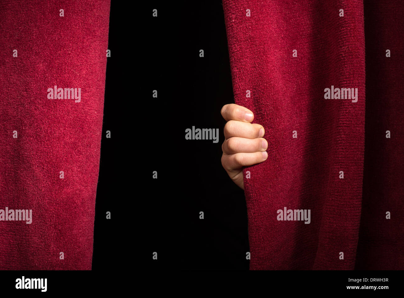 Hand appearing beneath the curtain. Red curtain. Stock Photo
